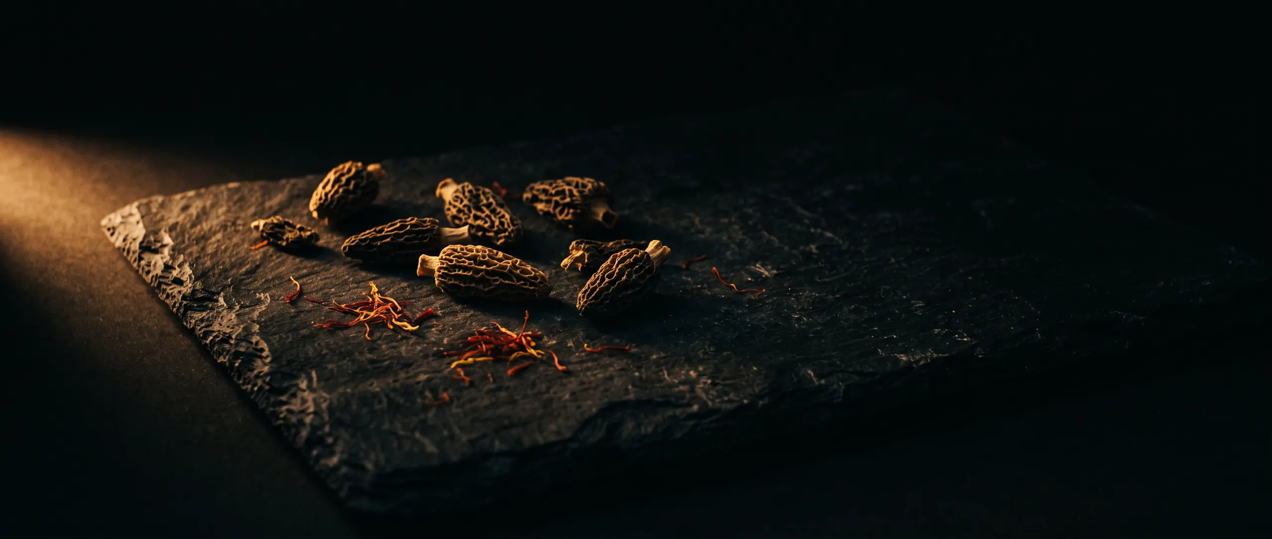 Black slate scattered with dried morels and saffron threads
